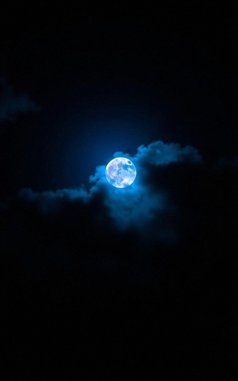 Glowing Blue Moon Emerging from Night Clouds